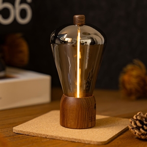 Bordlampe med træbase og dråbeformet glas, udsender varmt, gult lys.