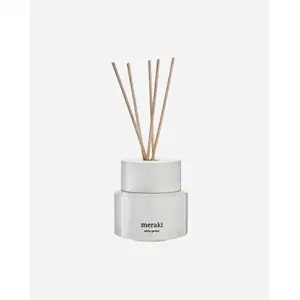 Hvid diffuser med meraki-logo og "white garden" påskrift, med flere træpinde i toppen.