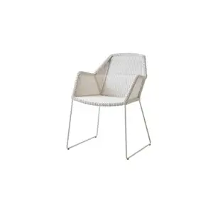 Hvid stol med armlæn, moderne design, vævet sæde og ryglæn, metalramme med slædelignende ben.