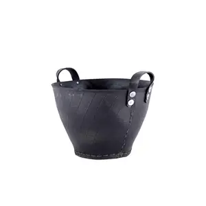 Sort kurv med tilspidset form, to håndtag med nitter og synlige syninger på siderne.