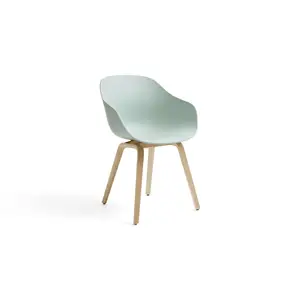Moderne stol med grøn skal, buet ryg og lyse træben.