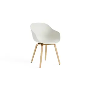 Minimalistisk stol med buet sæde, lave armlæn og lyse ben. Enkel og funktionel design.