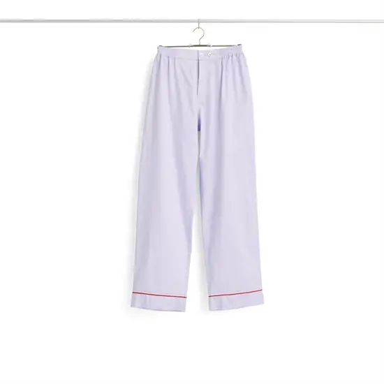 Lavendelfarvede pyjamasbukser fra HAY med rød kant ved manchetterne, hængende på en bøjle.