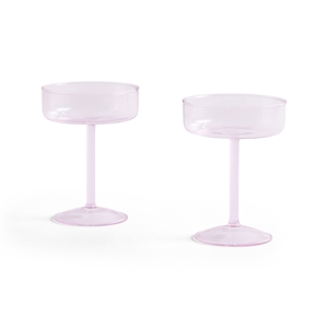 To lyserøde cocktailglas med stilk og bred skål, designet af Hay.