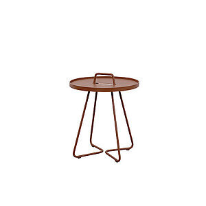 Rundt, lille sidebord i ørkenrød aluminium med håndtag og tre ben.
