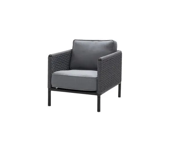 Mørkegrå loungestol med flettet design og grå hynder. Mørk ramme og ben med flettede armlæn.