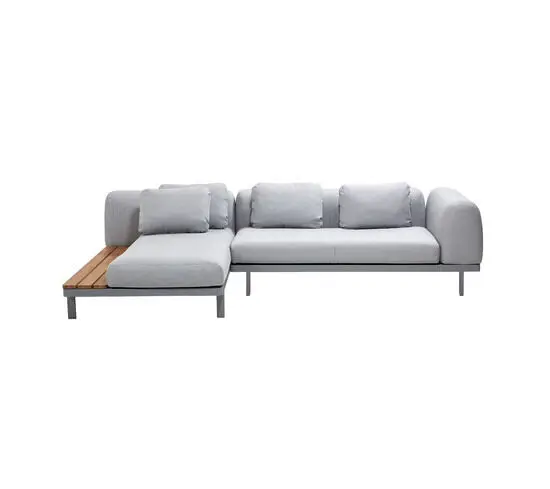 Modulsofa i lys grå med L-form, ryghynder og træudvidelse på den ene side. Minimalistisk design.