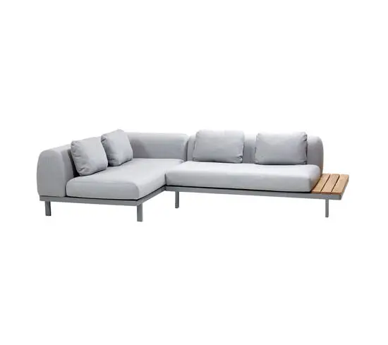 Lysegrå L-formet sofa med chaiselong til venstre og sidebord i træ til højre.