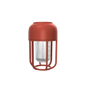 Rød, cylindrisk udendørslampe med solenergi. Kompakt design, stabil base til bærbar brug.