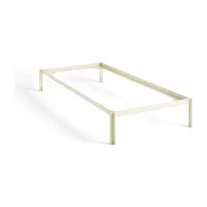 Minimalistisk sengestel i lys farve, rektangulært design uden hoved- eller fodgærde, fire ben.