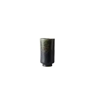 Lille, cylindrisk vase i mørkegrøn med lysere top, på rund sokkel.