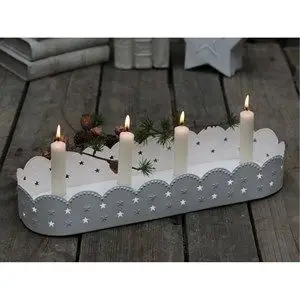 Hvid adventsstage med bølget kant og stjerner, holder fire lys på træoverflade.