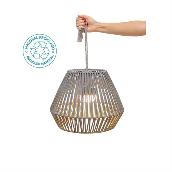 Hånd holder en flettet pendellampe med genbrugsmateriale-logo.