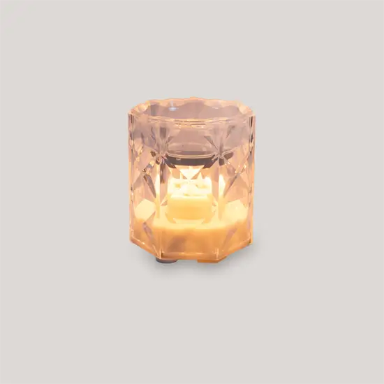 Klar, facetteret bordlampe med varm glød, ligner et stilfuldt lysglas.
