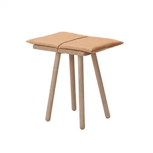 Skammel med fire runde ben og polstret sæde i to sektioner med synlig midtersøm.