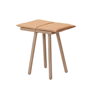 Skammel med fire runde ben og polstret sæde i to sektioner med synlig midtersøm.