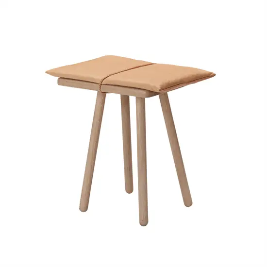 Skammel med fire runde ben og polstret sæde i to sektioner med synlig midtersøm.