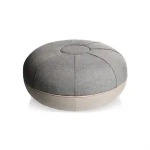 Rund grå puf med central knap, segmenteret syning, mørkere top og lysere bund.