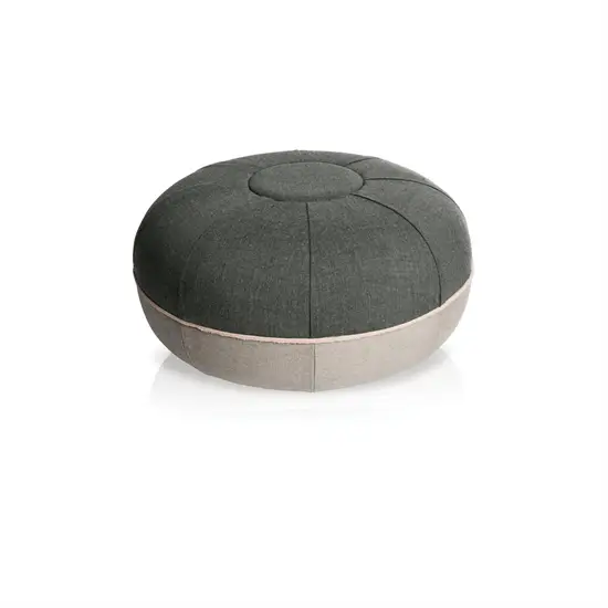 Rund pouf i stålgrå med mørk top, lysere base og synlige sømme fra midten.