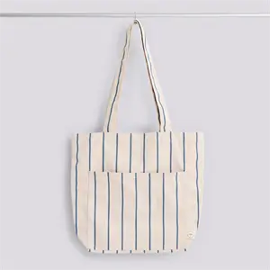 Beige tote bag med blå lodrette striber og to håndtag, perfekt til udendørs brug.