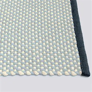 Tæppe i blød turkis og creme mønster med mørk kant. Viser designvariationer i farver.