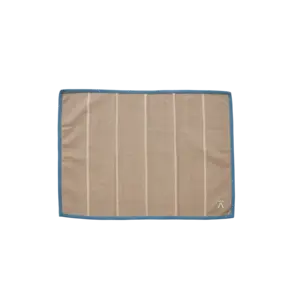 Beige dækkeserviet med lodrette striber, blå kant og logo i nederste højre hjørne.