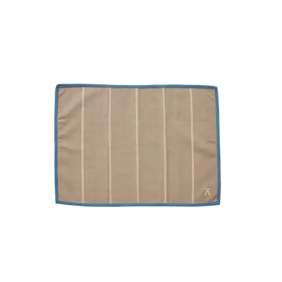 Beige dækkeserviet med lodrette striber, blå kant og logo i nederste højre hjørne.