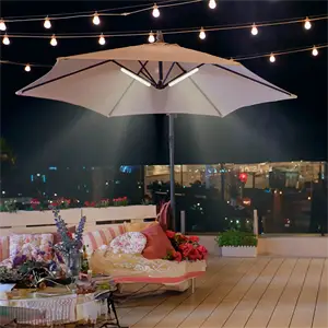 Parasol med indbygget lys på terrasse om natten, omgivet af lyskæder og hyggeligt møblement.