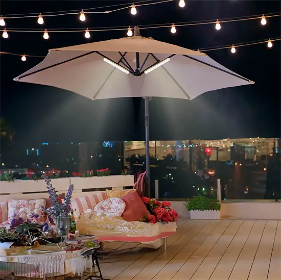 Parasol med indbygget lys på terrasse om natten, omgivet af lyskæder og hyggeligt møblement.