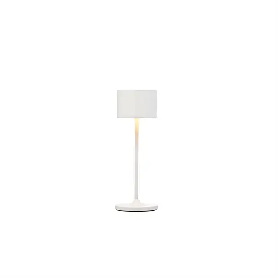 Hvid lampe med cylindrisk skærm, slank stang og rund base. Elegant og simpel design.