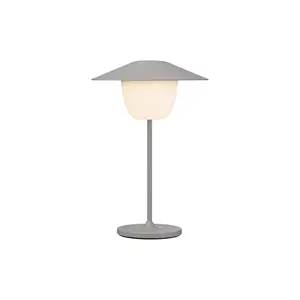 Moderne LED-lampe med konisk skærm og rund base, der udsender lys.