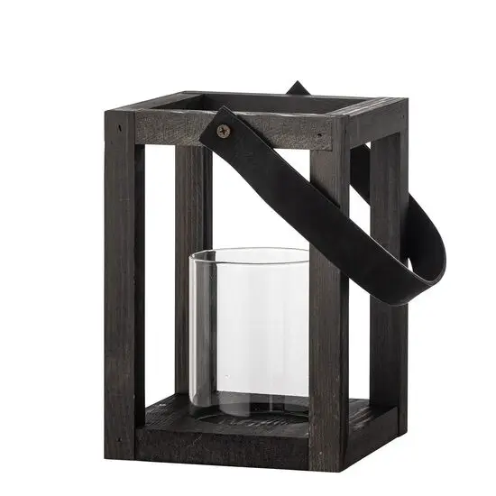 Sort lanterne med åben ramme, cylinderformet glasindsats og sort håndtag til bæring eller ophæng.