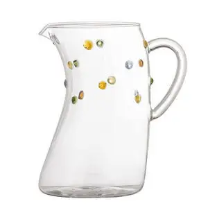 Klar glas kande med buet form, flerfarvede prikker og afrundet hank.