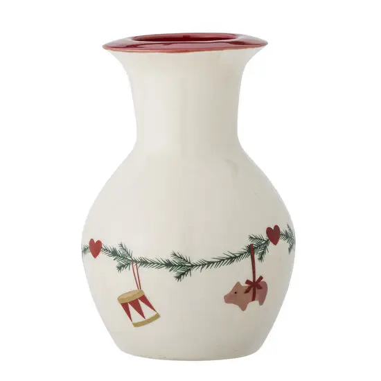 En vase med julemotiv: tromme, hjerter, grankvist og bjørn. Rød kant på toppen. Naturlig farve.