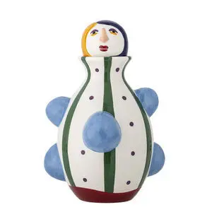 Keramisk vase med ansigt, grønne striber og blå kugleformede dekorationer på en hvid baggrund.
