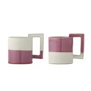 To keramikkrus med hvid top, pink-lilla bund og rektangulær hank. Cylindrisk form.