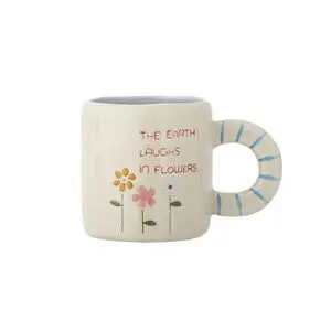Lys beige krus med blomstermotiver, tekst "THE EARTH LAUGHS IN FLOWERS" og blå striber på håndtaget.