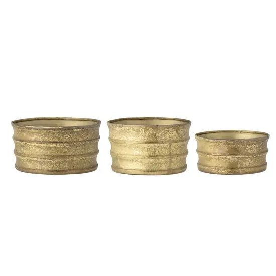 Tre guldfarvede metalpotter med rillet tekstur og forskellig størrelse. Lavet af jern.