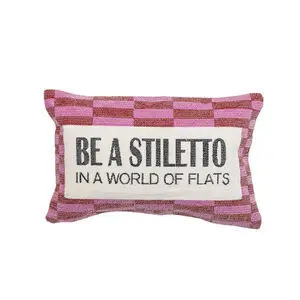Dekorativ pude med pink/hvidt mønster og tekst "BE A STILETTO IN A WORLD OF FLATS".