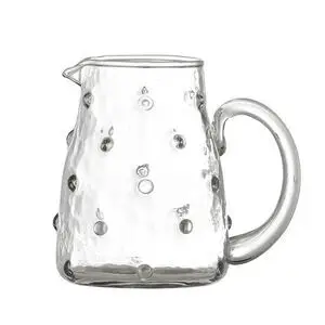 Klar glaskande med hævede cirkulære mønstre og stort rundt håndtag.