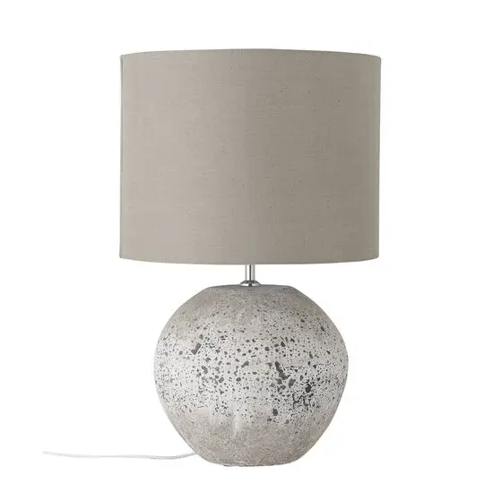 Bordlampe med beige skærm og rund stentøjsbase med mørke pletter.