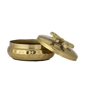 Rund gylden metalbeholder med hamret tekstur og låg med dekorativt element, let åbnet.