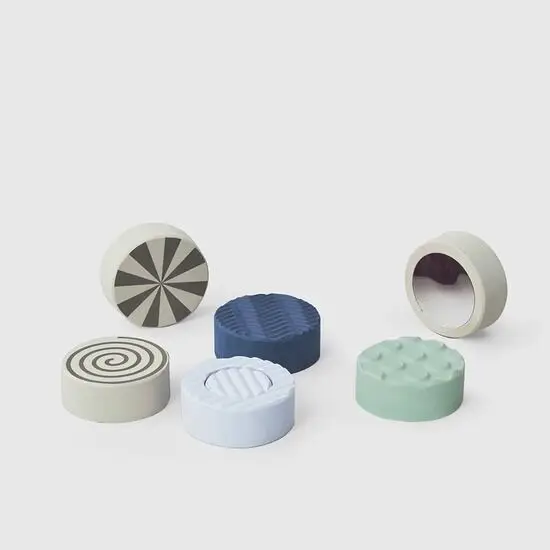 Seks runde sten med spiraler, riller og knopper i blå, grøn og beige.