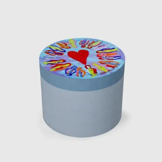 Blå cylinder med farverigt låg. Rødt hjerte omringet af abstrakte figurer på toppen.