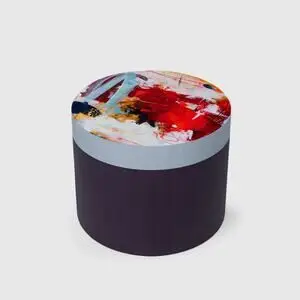 Cylinder med abstrakt mønstret top i røde, blå og gule nuancer, mørk ensfarvet side.