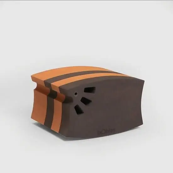 Kurvet objekt med orange og brune striber samt udskårne former på siden.