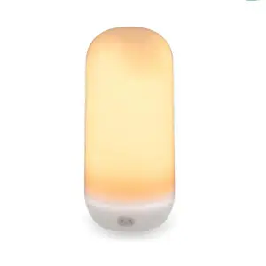 Cylindrisk bordlampe med hvid base og varm, blød glød.