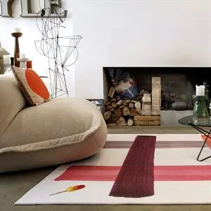 Stor, blød Fatboy lænestol i lys ecru med buet design og knapper, i moderne stue med pejs.