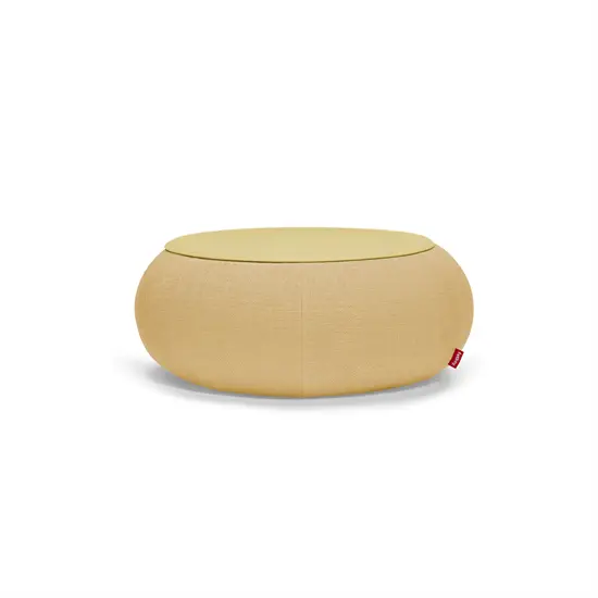 Rund puf med flad top, stofoverflade og rød tag. Cirkulært design i honningfarve.