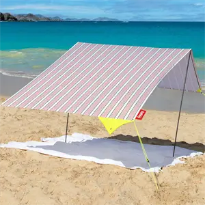 Bærbart strandtelt med lyserøde/hvide striber, opsat på sandstrand med hav og bjerge i baggrunden.